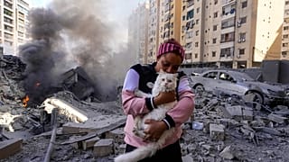 امرأة تحمل قطتها أمام مبنى مدمر في موقع غارة جوية إسرائيلية في الضاحية، بيروت، لبنان، الأربعاء، 2 أكتوبر/تشرين الأول 2024