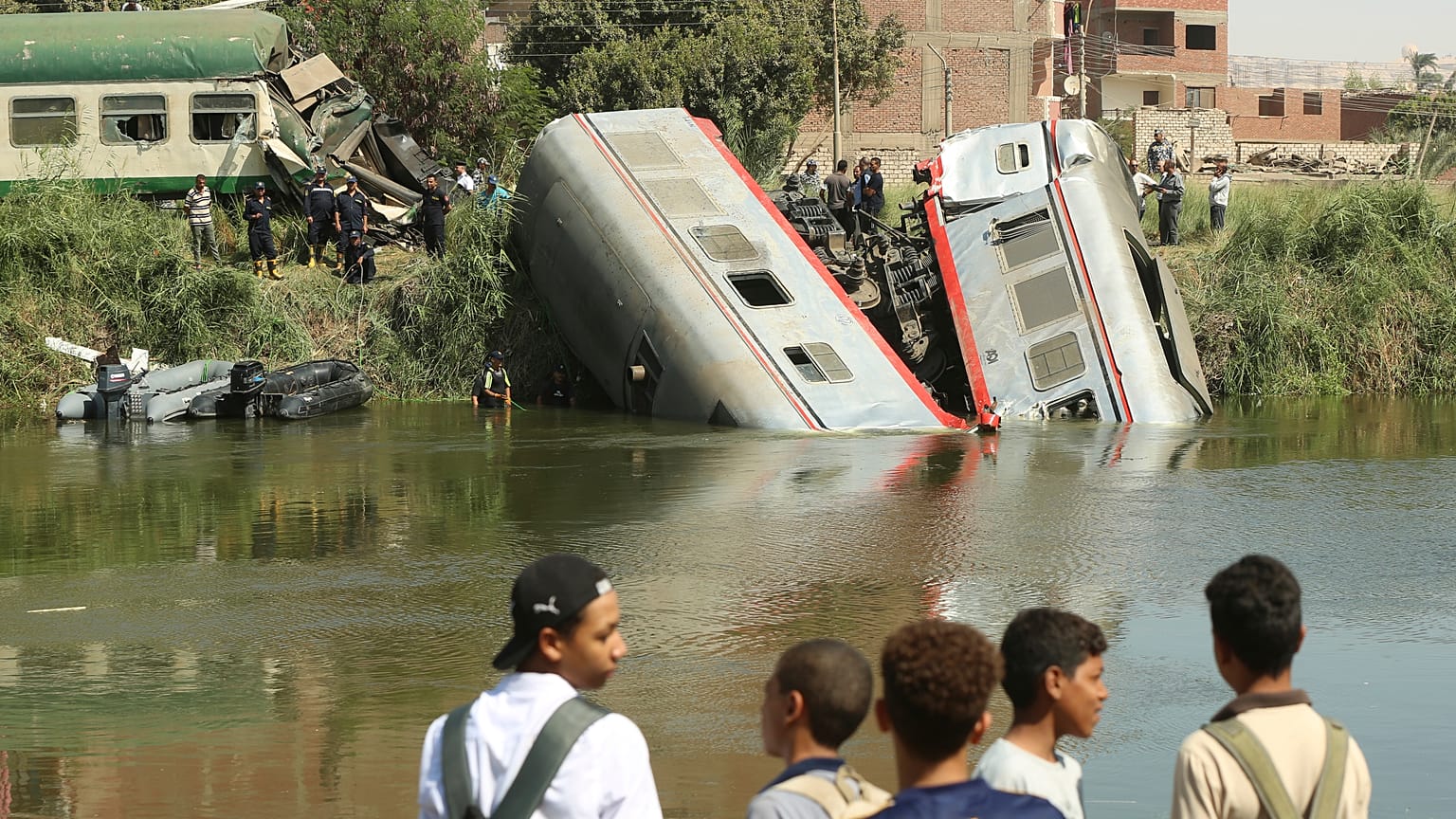 مواطنون مصريون يقفون قرب مكان حادث اصطدام قطار للمسافرين وسقوط عربتين في الماء أثناء توجه القطار إلى القاهرة. تاريخ: 13.10.2024
