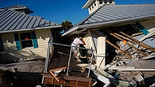 A property owner name peers into the remains of the second floor unit where he lived with his wife, on Manasota Key, in Englewood, Florida, on Sunday