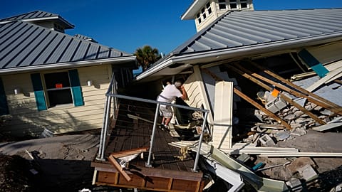 A property owner name peers into the remains of the second floor unit where he lived with his wife, on Manasota Key, in Englewood, Florida, on Sunday