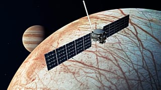 A NASA illusztrációján az Europa Clipper űrszonda látható az Europa közelében, a Jupiterrel a háttérben