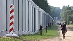 ARQUIVO - Guardas fronteiriços polacos patrulham um muro de metal na fronteira entre a Polónia e a Bielorrússia, perto de Kuznice, na Polónia.