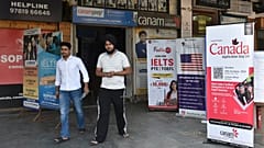 Hindistan'ın kuzeyindeki Pencap eyaletine bağlı Amritsar'daki bir pazarda, öğrencileri Kanada ve diğer ülkelerde okumaya davet eden pankartların önünden geçiyor, 15 Ekim 2024 