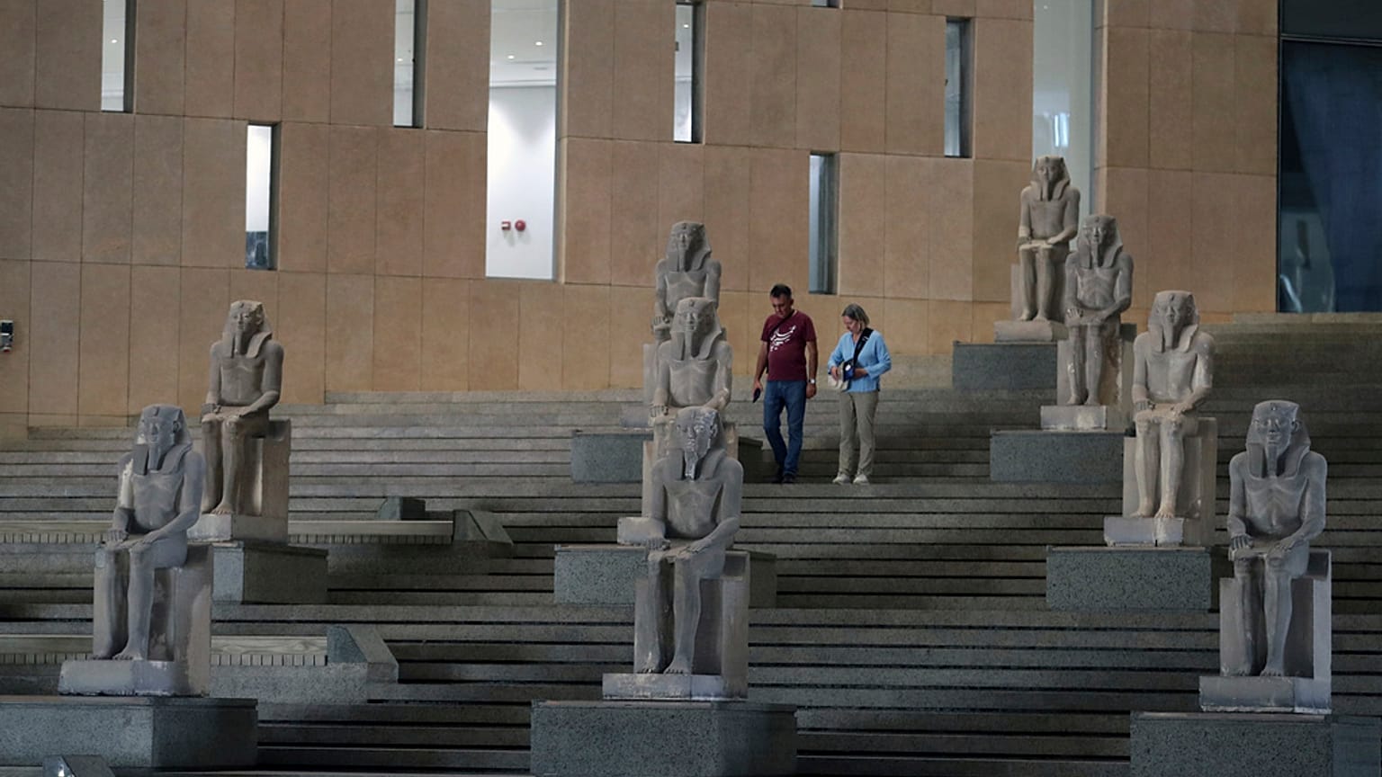 Ziyaretçiler, Büyük Mısır Müzesi'ndeki Büyük Merdiven boyunca antik Mısır heykellerinin yanından geçiyor.