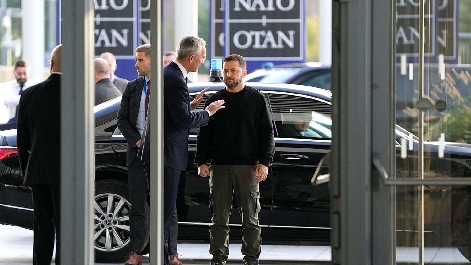 O antigo Secretário-Geral da NATO, Jens Stoltenberg, ao centro, à esquerda, fala com o Presidente da Ucrânia, Volodymyr Zelenskyy, à direita, antes de uma reunião dos ministros da Defesa da NATO