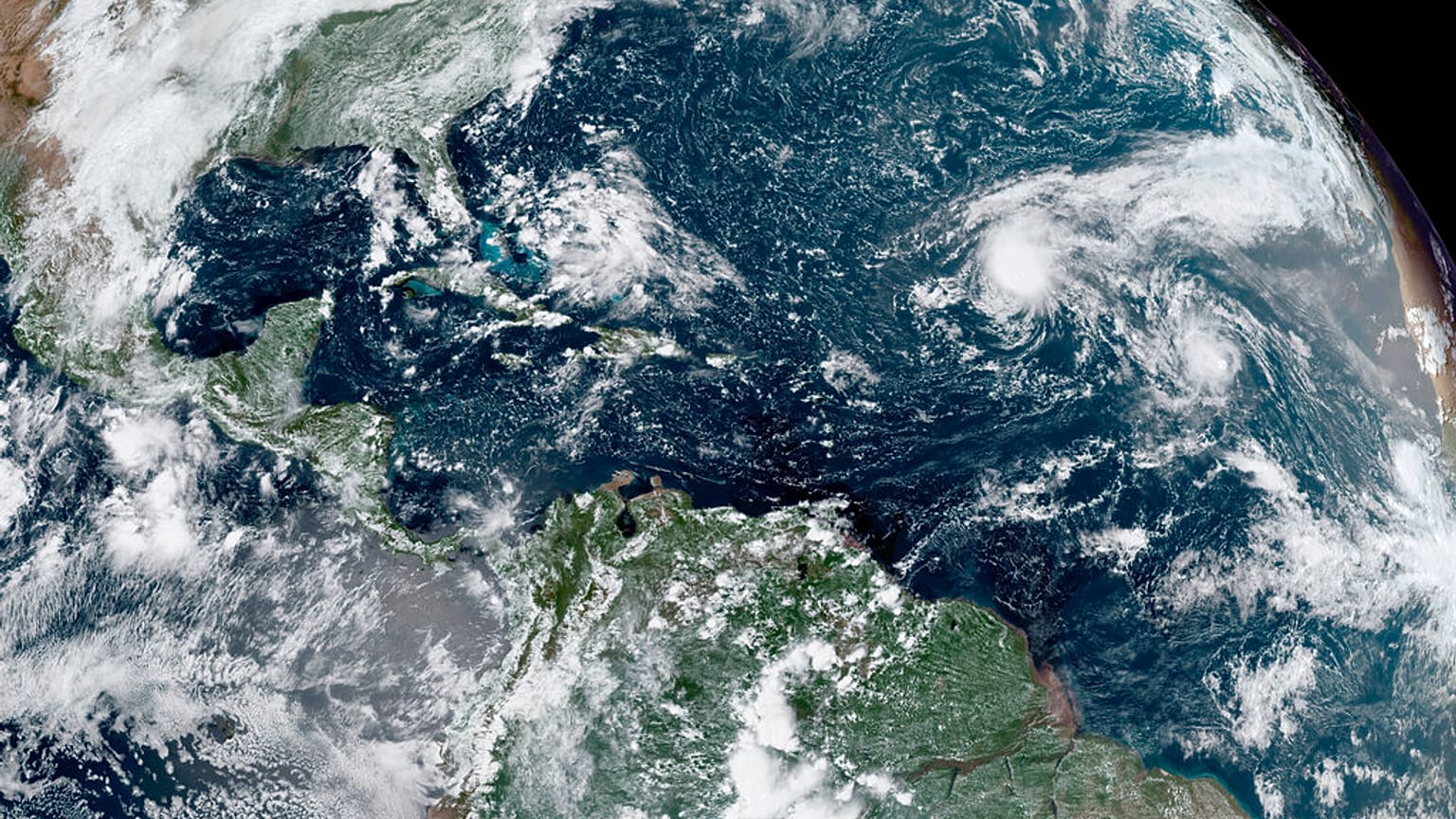 Изображение со спутника GOES-16 GeoColour, показывающее тропические штормы, формирующиеся в Атлантике.