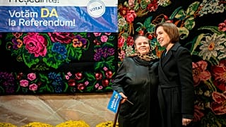 Moldova's President Maia Sandu, right, poses with a woman holding a flag reading "We Vote Yes to the Referendum" during an electoral meeting in Magdacesti, Moldova, Thursday, 