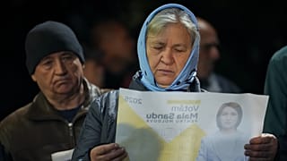 Une femme regarde un journal promouvant la présidente de la Moldavie, Maia Sandu, avant l'élection présidentielle de dimanche, le 17 octobre 2024.