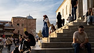 Pedestrians have a break at the stairs of Yeni Camii or New mosque in Istanbul, Turkey, Friday, Oct. 11, 2024. 