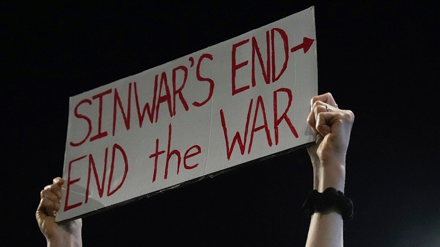 Bir gösterici, 17 Ekim 2024 Perşembe günü İsrail'in Tel Aviv kentinde, ateşkes anlaşması çağrısı yapan bir protesto sırasında Hamas lideri Yahya Sinvar'ın öldürülmesiyle ilgili bir pankart tutuyor. 