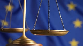 Scales of justice against a European flag