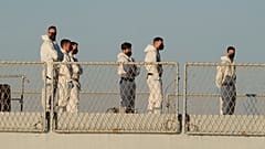 Sicherheitsbeamte stehen auf dem italienischen Marineschiff Libra.