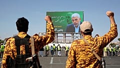جنديان يمنيان يحييان يحيى السنوار في لافتة ضخمة علقت على لوحة في العاصمة اليمنية صنعاء 18/10/2024