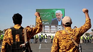 جنديان يمنيان يحييان يحيى السنوار في لافتة ضخمة علقت على لوحة في العاصمة اليمنية صنعاء 18/10/2024