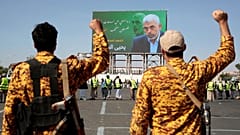 دو سرباز یمنی در حال شعار دادن مقابل بیلبوردی با تصویر سنوار در تاریخ ۱۸ اکتبر ۲۰۲۴
