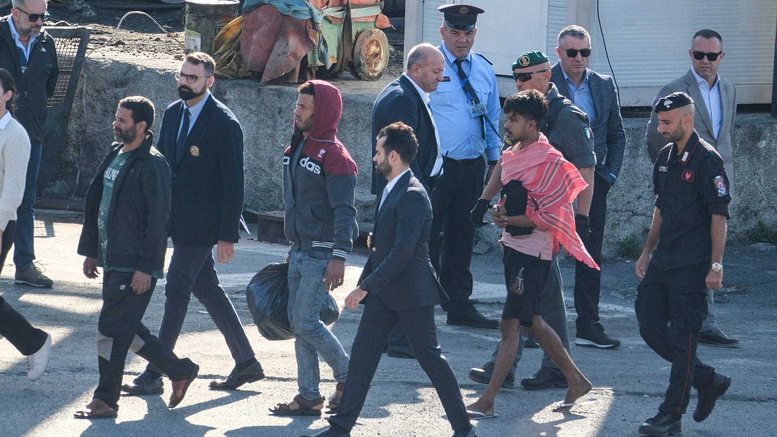 Migrant and security officials walk at the port of Shengjin, northwestern Albania. Wednesday, Oct. 16, 2024 