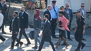 Migrant and security officials walk at the port of Shengjin, northwestern Albania. Wednesday, Oct. 16, 2024