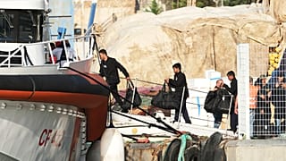 Férfiak szállnak fel az albániai Shengjinben lévő hajóra, amely Olaszországba viszi őket