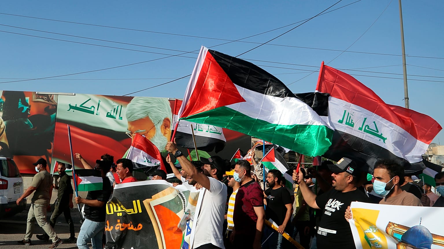 متظاهرون يهتفون بشعارات وهم يلوحون بالأعلام العراقية والفلسطينية دعماً للفلسطينيين في غزة خلال مظاهرة في بغداد، العراق، الخميس، 20 مايو/أيار 2021