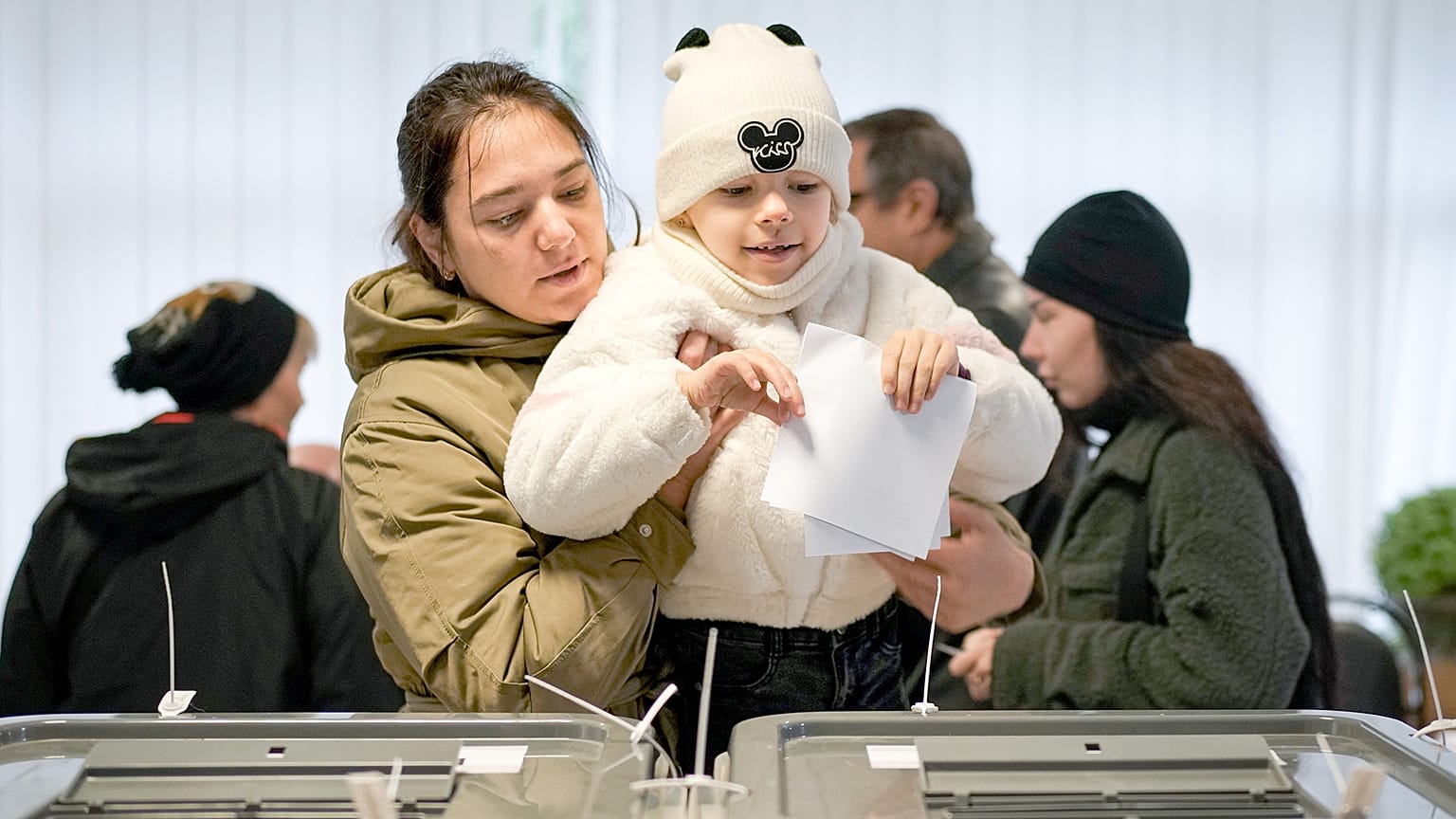 Una donna tiene in braccio un bambino mentre vota a Chisinau durante le elezioni presidenziali e il referendum sul futuro della Moldavia nell'Unione europea, 20 ottobre 2024.