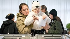 Una mujer sostiene a un niño mientras deposita su voto en Chisinau.