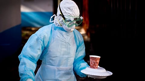 A medical worker wearing full protective equipment carries a meal to an isolation tent housing a man being quarantined for exposure to Marburg, 2014.