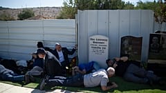 People take cover as a siren warns of incoming rockets during the funeral of Alexei Popov