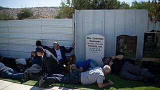 People take cover as a siren warns of incoming rockets during the funeral of Alexei Popov