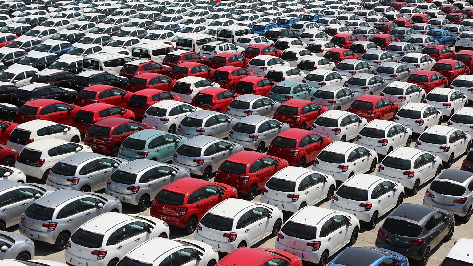 Várias filas de carros estacionados num parque de estacionamento