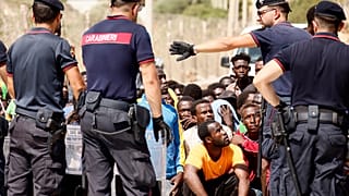 Ιταλοί αστυνομικοί περιφρουρούν διαδήλωση μεταναστών έξω από κέντρο φιλοξενίας στη Σικελία