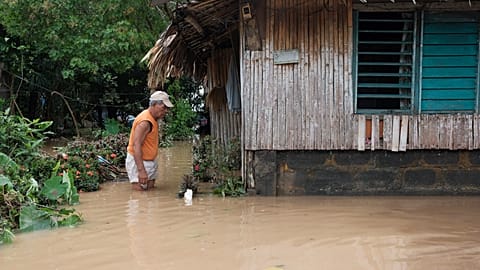 Tropikal fırtına Trami'nin sular altında bıraktığı evinin önünde duran bir adam, Albay eyaleti, Filipinler, 23.10.2024