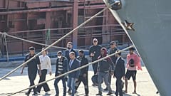 Μετανάστες και αξιωματικοί περπατούν στο λιμάνι του Shengjin της Αλβανίας. Τετάρτη 16 Οκτωβρίου 2024, μετά την αποβίβαση από το πλοίο Libra του Πολεμικού Ναυτικού που μεταφέρει τους πρώτους 16 μετανάστες