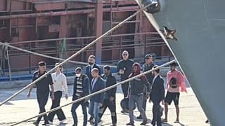 Migranten und Offiziere gehen im Hafen von Shengjin, Albanien, spazieren. Mittwoch, 16. Oktober 2024, nach der Ausschiffung der ersten 16 Migranten von dem Marineschiff Libra