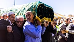 Pall-bearers carry the casket into the stadium