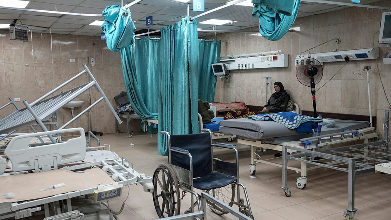 صورة أرشيفية لسيدة فلسطينية جالسة في غرفة بمشفى شهداء الأقصى في دير البلح حيث تظهر آثار القصف الإسرائيلي عليه