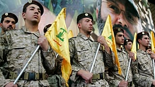 مقاتلو حزب الله يحملون رايات حزبهم ويقفون بجوار صورة قائدهم عماد مغنية، خلال حضورهم تجمعًا لإحياء ذكرى مغنية وعباس الموسوي وراغب حرب