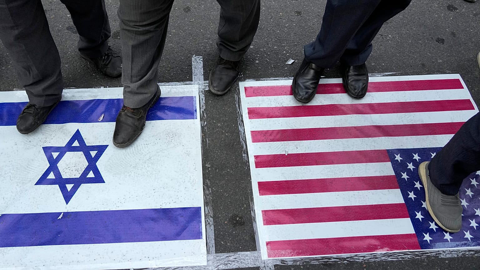 ARCHIVO - Manifestantes iraníes se paran sobre banderas de EE.UU. e Israel en una concentración anti-israelí en la Plaza Felestin (Palestina) en Teherán, Irán, martes 8 de octubre de 2024.