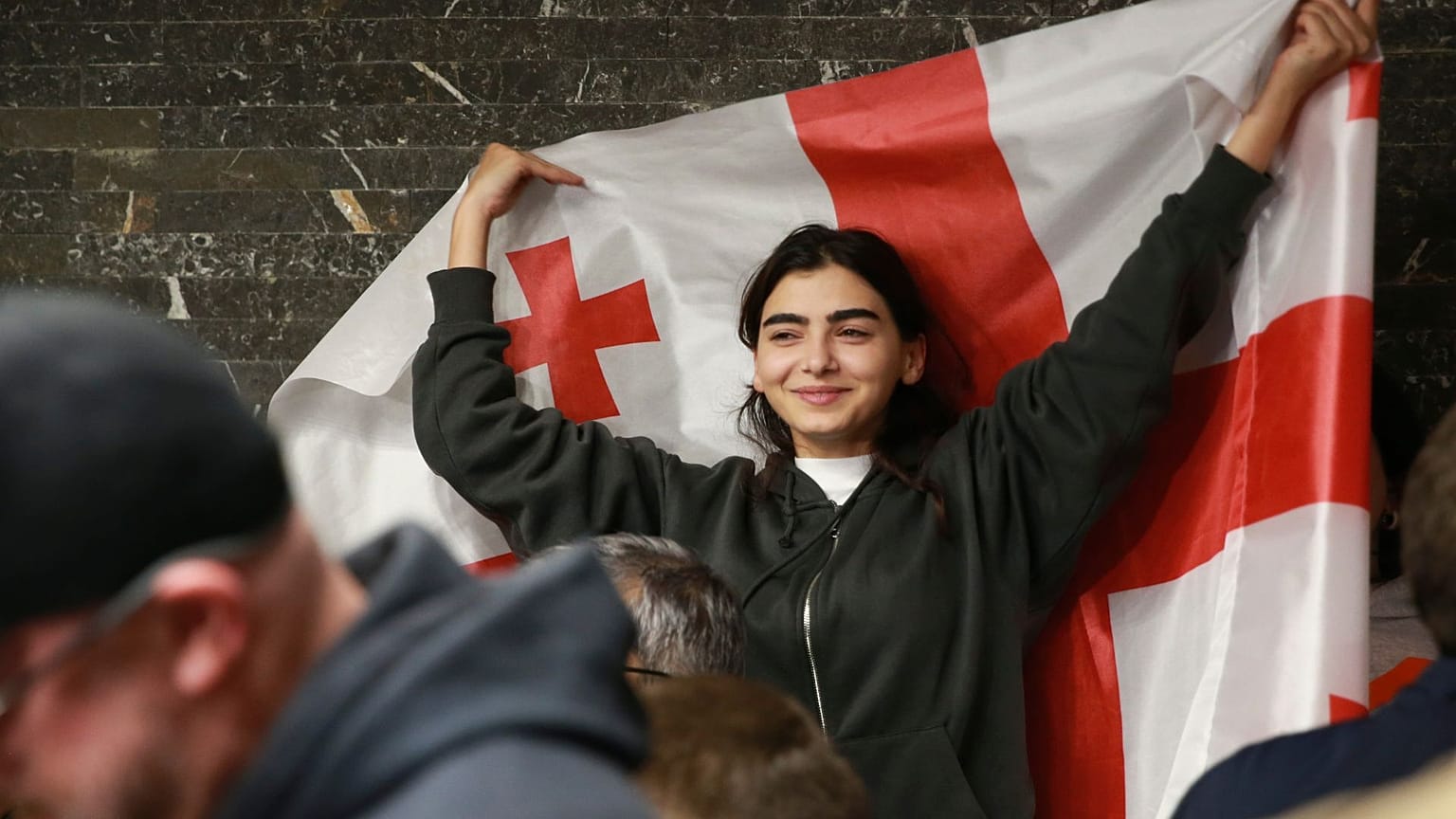 یکی از حامیان حزب ائتلاف برای تغییر با پرچم گرجستان پس از بسته شدن شعب رای گیری در انتخابات پارلمانی تفلیس، گرجستان، شنبه، ۲۶ اکتبر ۲۰۲۴، 