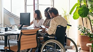 Ομάδα με άτομο με αναπηρία που εργάζεται σε γραφείο.