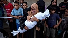 سيدة فلسطينية تحمل جثة طفلة بين يديها قتلت بغارة إسرائيلية على دير البلح بقطاع غزة