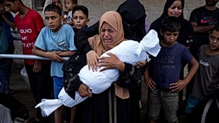 سيدة فلسطينية تحمل جثة طفلة بين يديها قتلت بغارة إسرائيلية على دير البلح بقطاع غزة