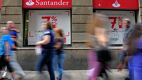 In this photo taken on Tuesday Oct. 22 2013, people walk past a Santander bank branch in Barcelona, Spain. 