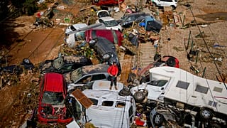 A man stands among flooded cars piled up in Valencia