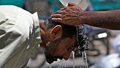 Ein Freiwilliger gießt einem Mann Wasser über den Kopf, um sich an einem heißen Sommertag in Karachi, Pakistan, abzukühlen