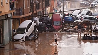 أشخاص يسيرون في شوارع غمرتها المياه في فالنسيا، إسبانيا