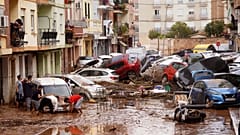 Residentes limpian la calle junto a los coches amontonados tras ser arrastrados por las inundaciones en Valencia, España, miércoles 30 de octubre de 2024. 