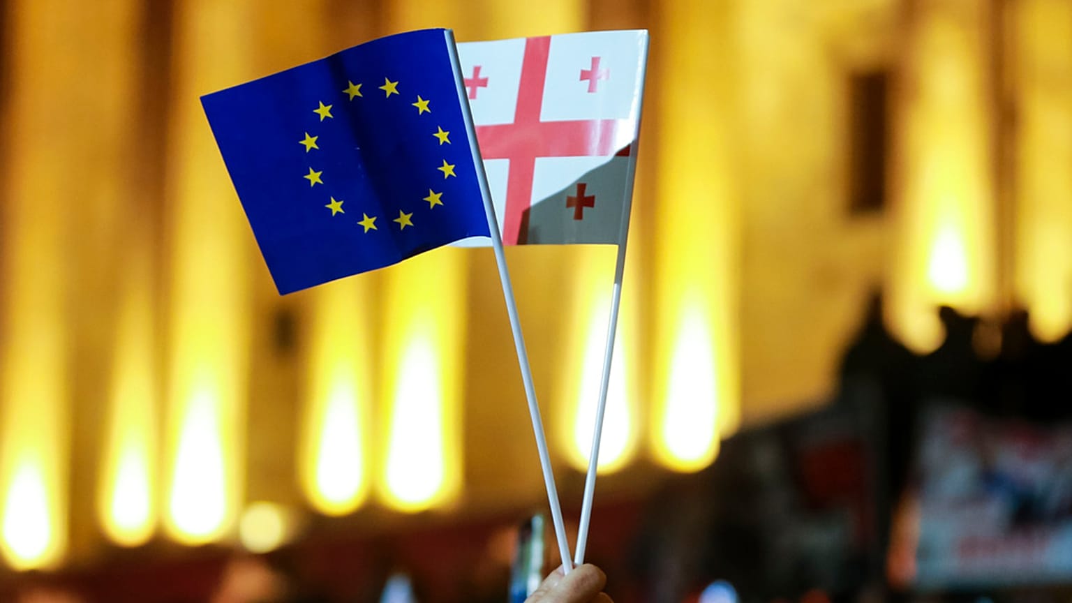 Egy tüntető uniós és grúz nemzeti zászlót lenget a parlamenti választások eredményei elleni ellenzéki tüntetésen a grúziai Tbilisziben 2024. október 28-án.
