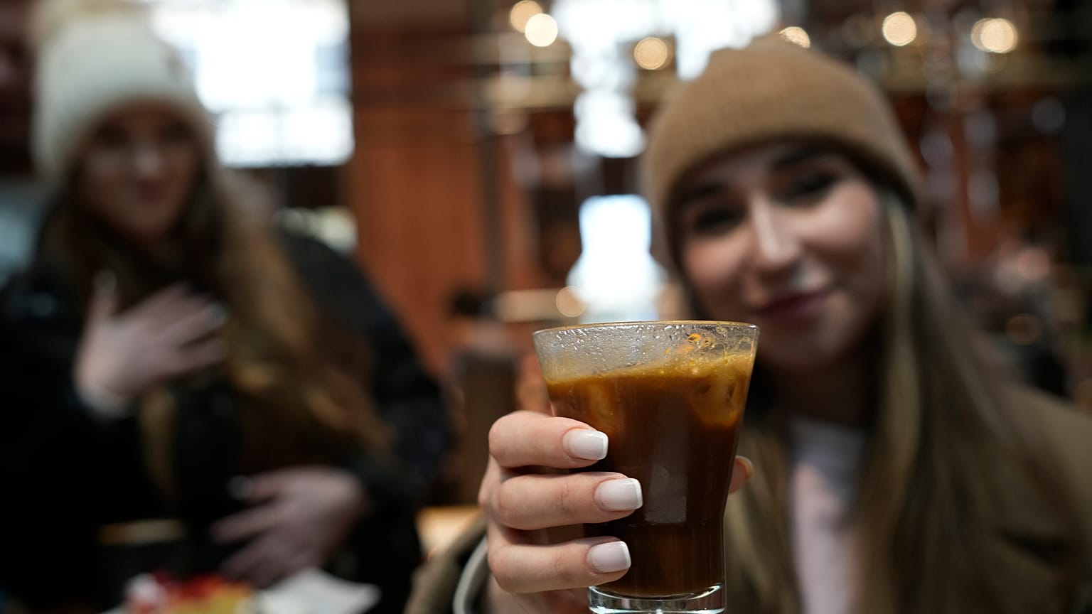 FILE - Kaya Cupial, right, shows her Oleato Iced Cortado coffee at the Starbucks coffee shop in Milan, Italy, Feb. 27, 2023. 