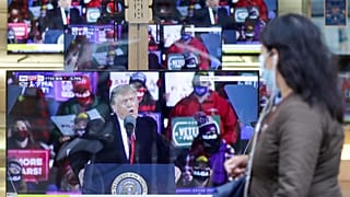 Milano'da bir kadın, 2020'de ABD Başkanı Donald Trump'ı gösteren televizyon ekranlarının önünden geçiyor.