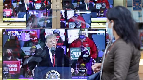 A woman in Milan walks by TV screens showing then-US President Donald Trump in 2020.